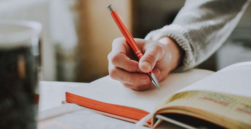 person writing on a diary