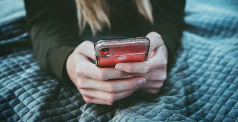 woman checking her phone on her bed