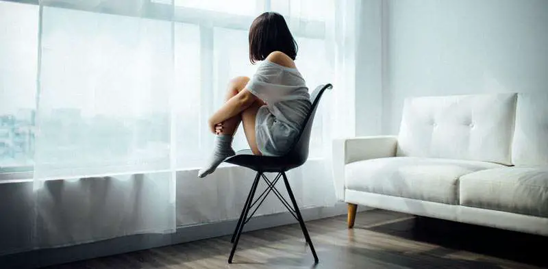 girl alone seated looking through the window