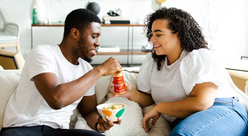 couple on a couch sharing snacks