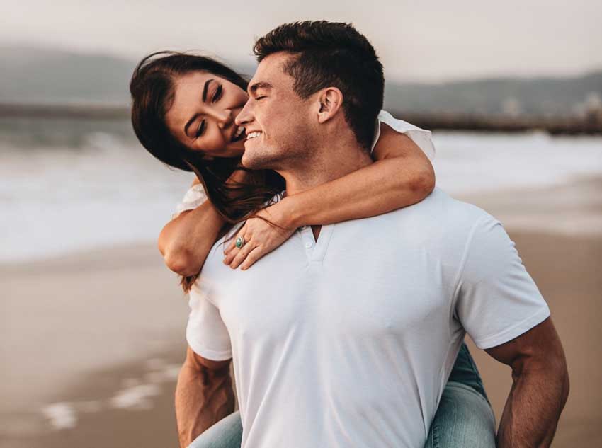 man carrying a woman on the beach