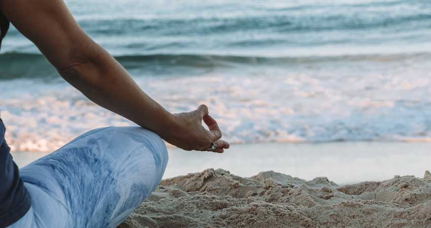 someone meditating on the beach