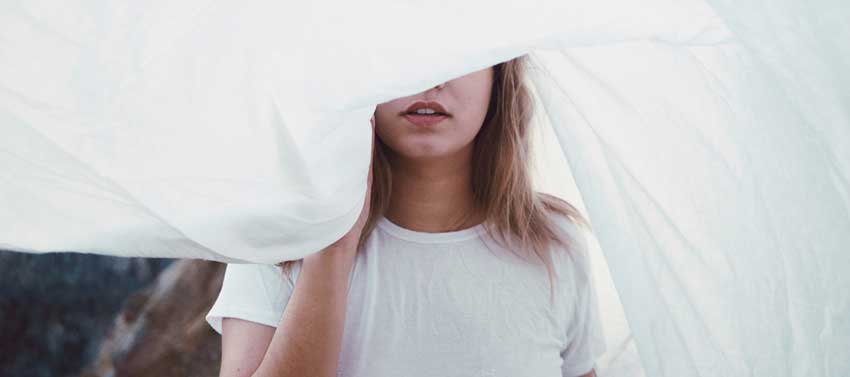 shy person hiding behind a bed sheet