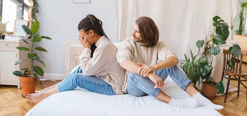 woman feeling sad with boyfriend on the bed